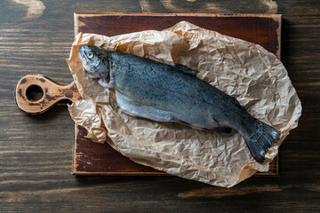 One raw fish trout on a cutting board, closeup, top view