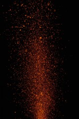 Fototapeta premium Intense orange and red sparks erupting upwards on a pure black background