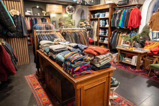 Interior of trendy fashionable men's clothing vintage store with various assortment of clothes and accessories displayed on hangers and table, fancy apparel showcased in old fashioned second hand shop