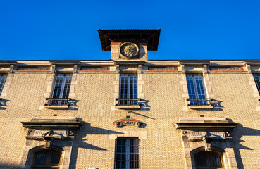 Historic building of College Josephine Baker stands in Saint-Ouen-sur-Seine, France. Brick architecture features inscriptions for boys and girls schools and a central clock under a blue sky