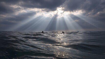 Dramatic sunbeams break through stormy clouds over the ocean illuminating swimmers in the water