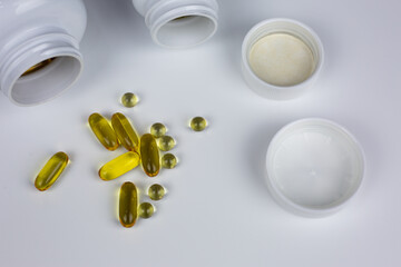 Yellow capsules with Omega 3 and D3 vitamins. Set of dietary supplements on white background. Scattered tablets. Concept of taking vitamins in capsules and tablets