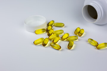 Soft gels pills with Omega-3 oil spilling out of pill bottle close-up. Gel capsules and jar. Omega 3, multivitamins, Calcium and antibiotics. Health and Immunity concept with dietary supplements