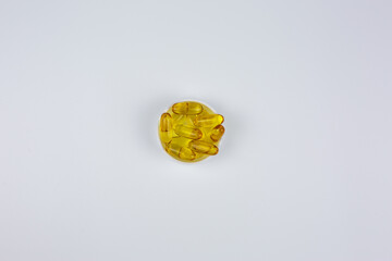 Vitamin D, omega 3, omega 6. Food supplement oil filled fish oil, flaxseed oil. Yellow dietary supplement capsules in lid on white background. Omega 3 capsules are in center of frame