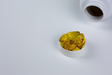 Set of Omega 3 fish oil capsules in jar lid on white background with space for text. Concept for using dietary supplement to maintain health. Universal vitamins and wellbeing