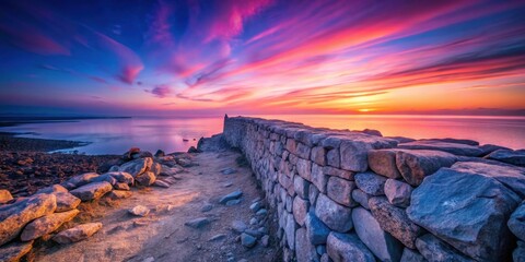 Serene coastal stone wall at sunset, overlooking tranquil ocean waters reflecting vibrant sky hues