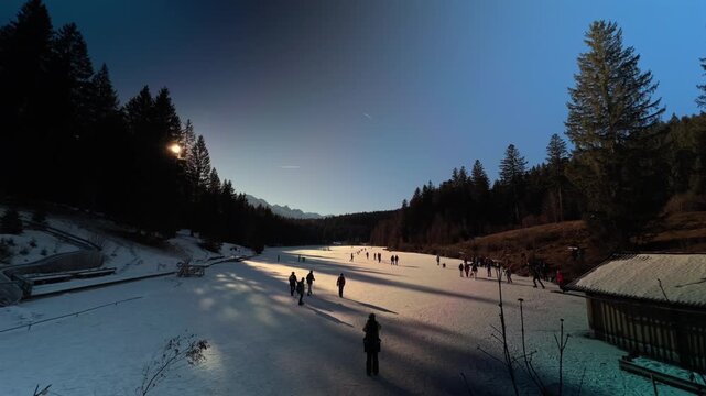 Lake Grubsee, Garmisch-Partenkirchen district, Upper Bavaria, Germany. Active lifestyle at the frozen Grubsee. People enjoying ice skating and hockey. Eislaufen auf dem gefrorenen Grubsee bei Kruen