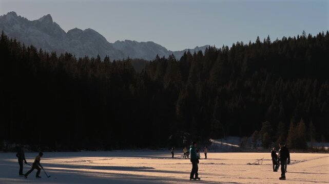 Lake Grubsee, Garmisch-Partenkirchen district, Upper Bavaria, Germany. Winter sports in Kruen. Families ice skating on frozen lake. Pristine nature, cold fresh air and beautiful Bavarian Alps scenery