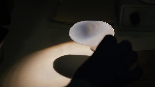 Laboratory optics experiment showing a circular filter shaping a focused light beam, projecting a visible spectrum and concentric interference patterns onto paper