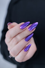 Woman hand with long nails and a bridht purple nail polish