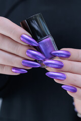 Woman hand with long nails and a bridht purple nail polish
