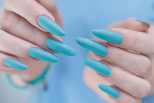 Woman's beautiful hand with long nails and light baby blue manicure