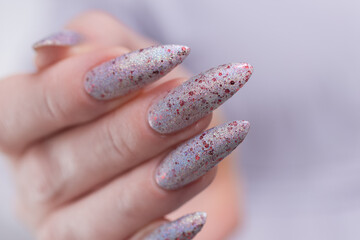 Female hand with long nails and a white gray silver and red manicure