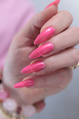 Female hand with long nails and a bright neon pink color nail polish