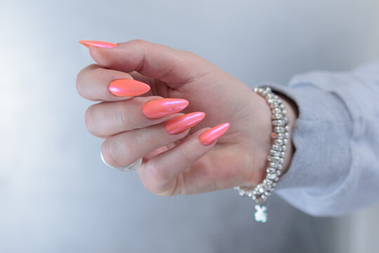 Female beautiful hand with long nails and a bright orange nail polish