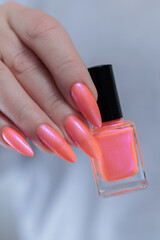 Female beautiful hand with long nails and a bright orange nail polish