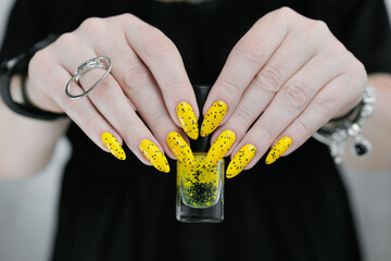 Female beautiful hand with long nails and a yellow and black nail polish	