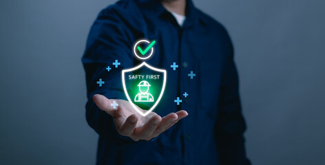 concept of safety first. man's hand showing protective shield and worker icon, representing workplace safety, industrial protection, risk management, health compliance and modern safety technology