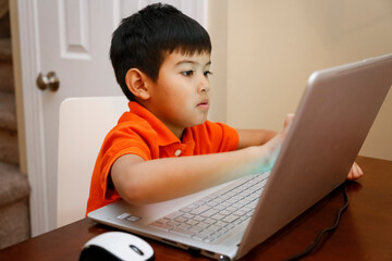 Philadelphia, PA, USA. Native American young boy doing his homework on his laptop