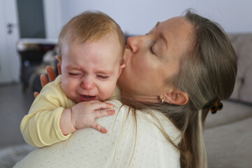 Mother soothing her crying baby. Background.