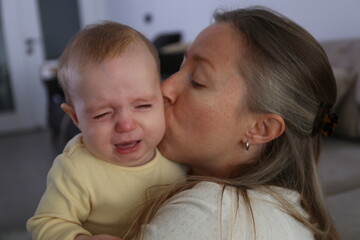 Mother soothing her crying baby. Background.
