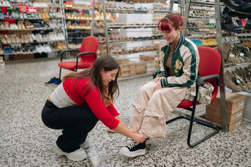 Woman helping customer trying on new shoes in store