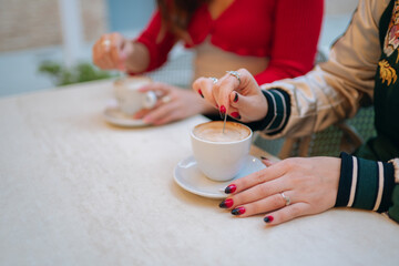 Women stirring coffee in a cafe on a table
