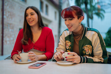 Young women friends enjoying coffee and talking outside