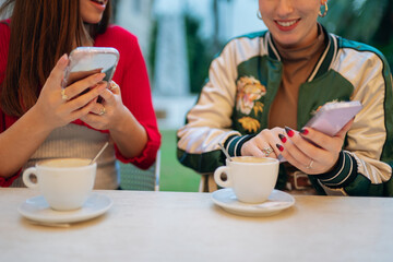 Women sitting at outdoor cafe using smartphones