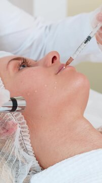 Injection-free mesotherapy or electroporation. Beautician doctor makes client young adult woman face therapy in beauty clinic salon. Girl skin care anti-age spa procedure indoor aesthetic cosmetology