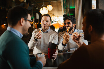 Group of cheerful friends eating salty pretzel sticks and chatting while waiting for their beer...