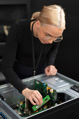 Female IT technician in her thirties, Caucasian, upgrading server hardware inside a metal rack