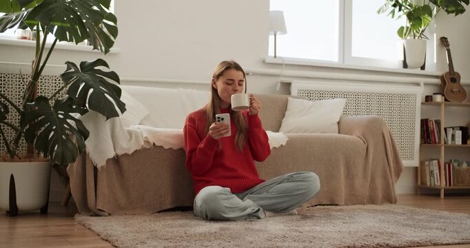 Young woman drinking coffee and using smartphone