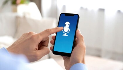 Hand of a person touching smartphone screen with microphone icon in modern living room, voice recognition technology concept for communication