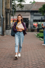 University student walking on campus holding books and notebook