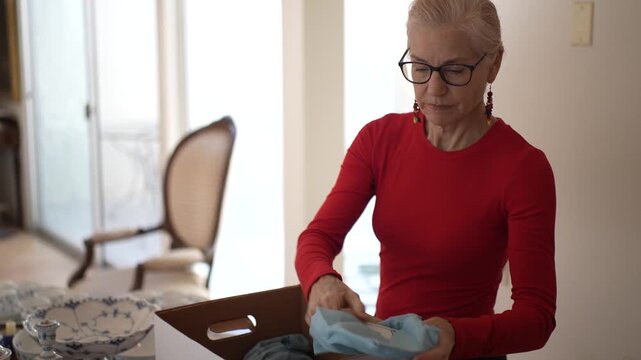 Mature woman unpacks her inherited china dining sets and reflects on family memories and the love shared over meals together.