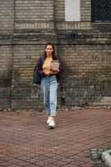 University student walking on campus holding books and laptop