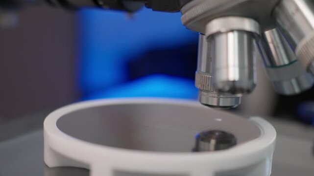 Close-up view of microscope objective focusing on a silicon wafer during high-precision semiconductor inspection, highlighting optical components and precise research.