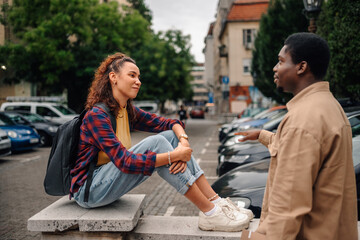 Two students talking and gesturing in university campus parking lot