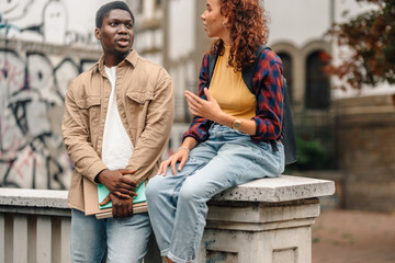 Two college students chatting on campus wall