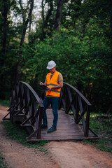 Forest engineer taking notes on wooden bridge