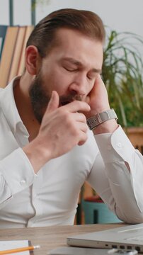 Bored sleepy middle eastern businessman worker working on laptop computer, yawning, leaning on hand falling asleep at office. Exhausted tired freelancer workaholic man. Employment, occupation workless