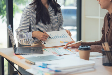 Business strategy planning: An overhead view of two professionals collaborating over a business strategy plan on desk, engaged in a discussion analyzing the data and making decision
