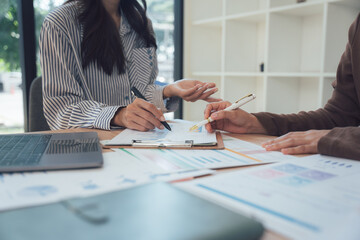Strategic Planning Session: Two professionals engage in a focused discussion over a detailed business plan, marked with data, insights, and analytical data.