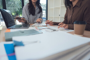 Collaborative Workspace: Two women are engrossed in a focused discussion, analyzing data and strategizing over important documents.