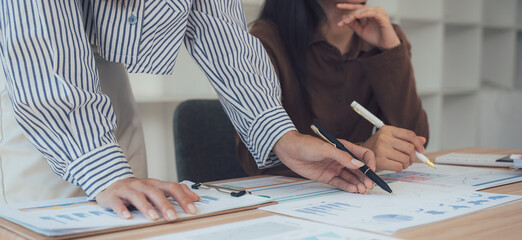 Focused Business: Two professionals collaborate, meticulously reviewing documents and charts at a desk, their combined efforts are driven by a shared vision