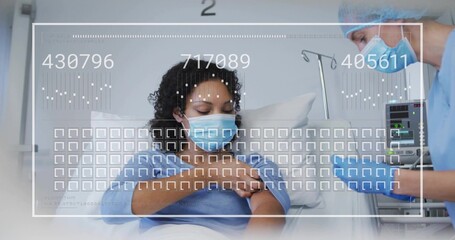 Reclining patient wearing surgical mask, gown receiving care in bay 2, nurse leaning in blue scrubs