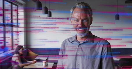 Smiling man standing at right in cafe, wearing gray shirt, woman at left working, glitch lines