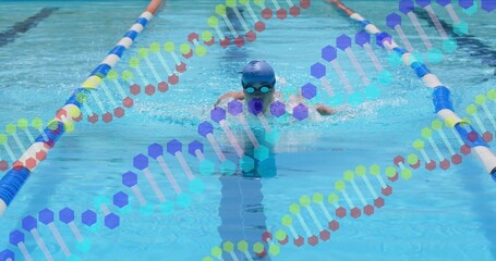 Swimming male doing forward stroke in lap pool, wearing blue cap, swimwear, lane ropes, DNA