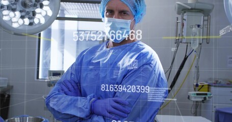 Standing surgeon arms-crossed wearing blue gown, cap, mask and gloves in OR, IV pole, HUD overlays